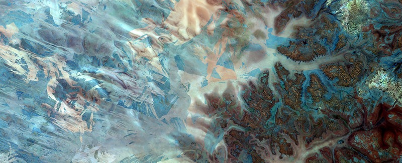 Image satellite en fausses couleurs du désert de Gibson, montrant des formes étranges dans différentes teintes de bleu.